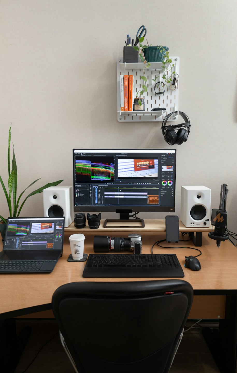 Videoschnitt-Arbeitsplatz mit Computermonitoren und Geräten auf einem Schreibtisch.