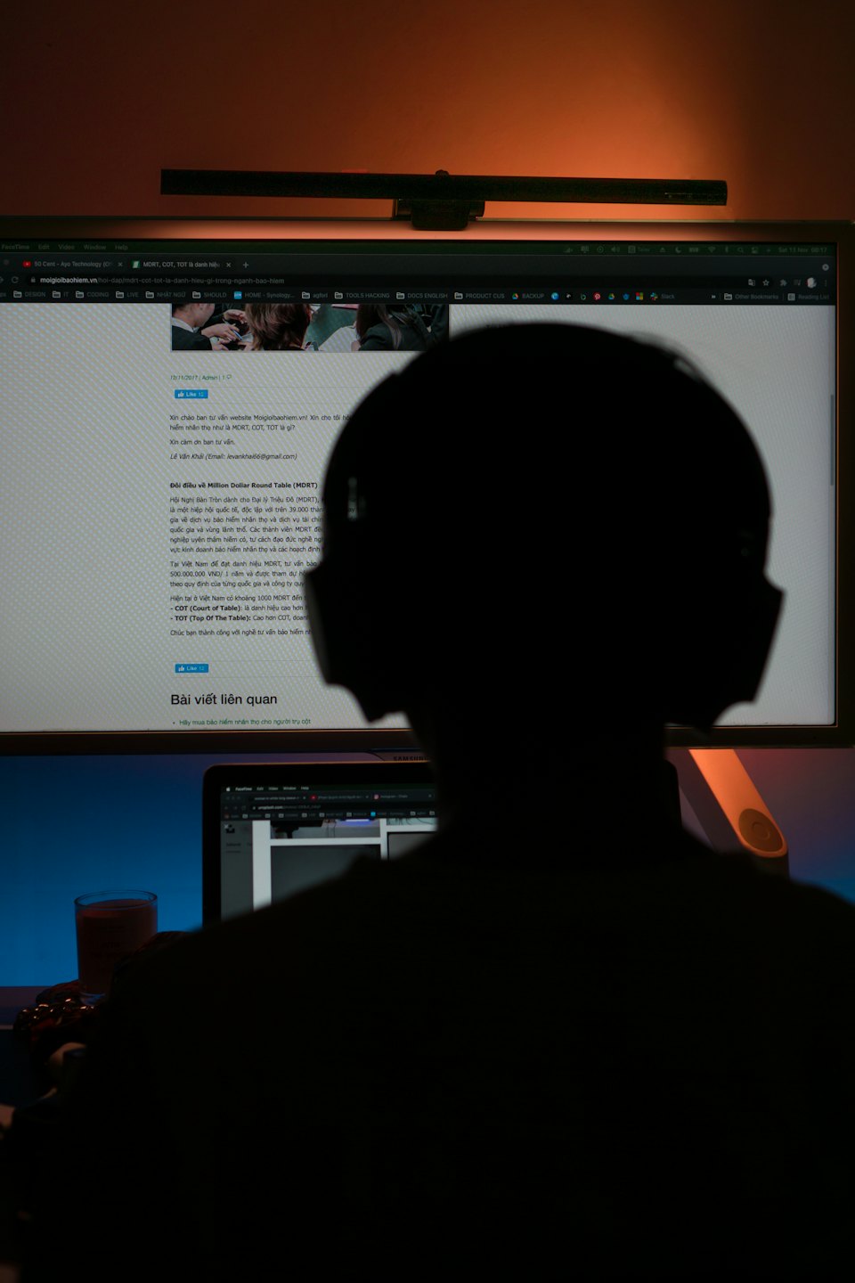Eine Person mit Kopfhörern arbeitet an einem Schreibtisch mit zwei Monitoren.