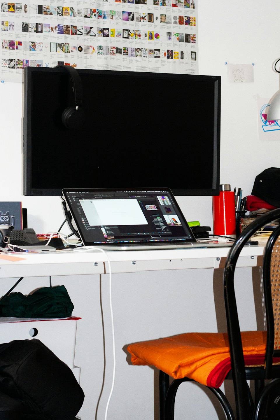 Ein unordentlicher Schreibtisch mit Laptop und Monitor, auf denen Videosoftware angezeigt wird.