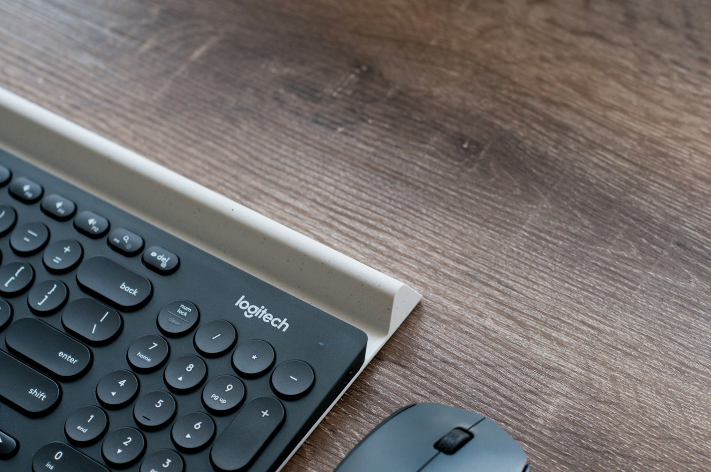 Eine moderne kabellose Tastatur und Maus auf einem Holztisch.