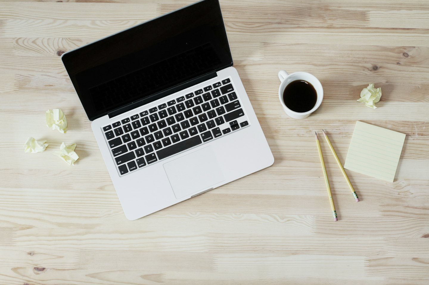 Schreibtisch mit Laptop, Kaffee und gelben Büromaterialien.